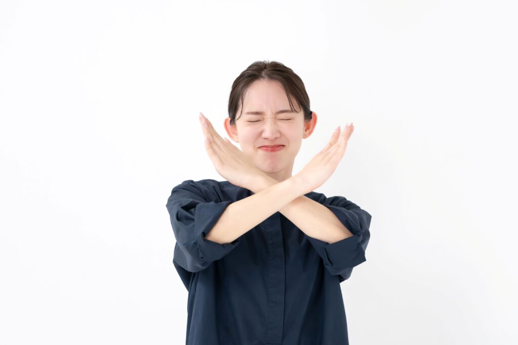 バツサインを出す女性の写真